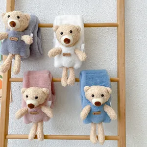 Plush kids bear scarves in gray, white, pink, and blue hanging on a wooden ladder