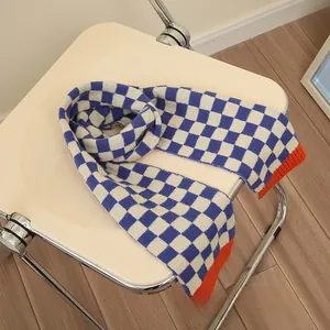 Detail of soft blue and white checkered knit scarf with vibrant orange contrast edges