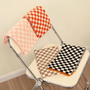 Kids checkered knit scarf in orange, pink, brown, and black patterns on a chair