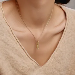 Détail du collier pendentif MAMA doré avec zircons sur un pull en maille douce