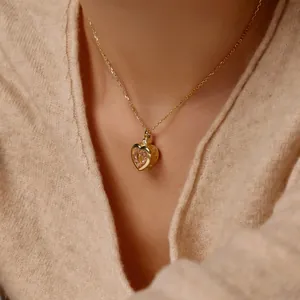 Close-up of heart pendant necklace with pink crystal on neck in beige sweater