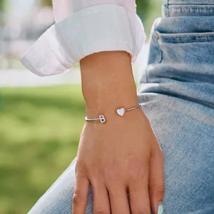 Detail eines silbernen B-Buchstaben-Armbands mit Herzbesatz in natürlichem Licht