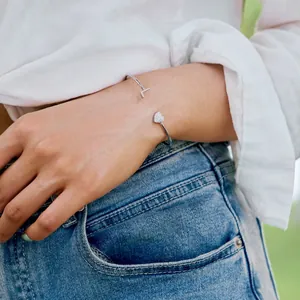 Nahaufnahme des S925 Silber-Armreifs mit Herz- und T-Charms am Handgelenk
