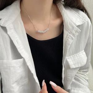 Gros plan du collier en argent 925 avec sept fleurs en zircone sur une fine chaîne de clavicule