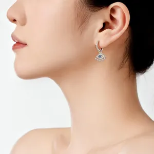Primer plano de modelo con pendientes de plata 925 de ojo turco con piedras de circón azul