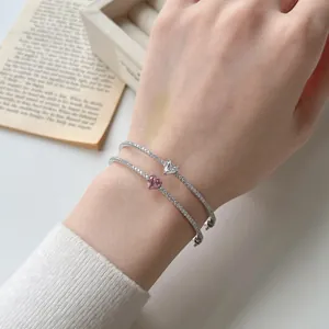 Nahaufnahme zweier silberner Armbänder mit herzförmigen rosa und weißen Zirkonia-Steinen