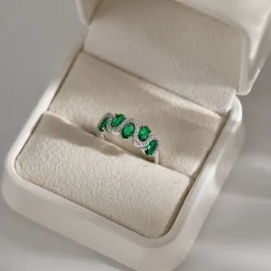 Detail of s925 silver ring with five oval green gemstones and diamonds in a gift box
