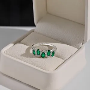 Detailed shot of S925 silver ring with five oval emerald stones in a luxury gift box