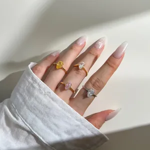 Dettaglio di anelli con zirconi a forma di pera in oro e argento per uno stile a strati