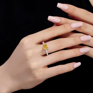 Close-up of heart-shaped yellow gemstone ring with pavé diamonds on finger