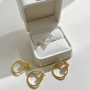 Close-up of pear-cut sparkling zircon rings in gold and silver settings on white leather