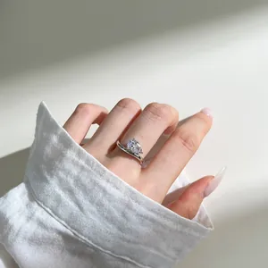 Macro view of pear-cut water drop cubic zirconia ring on finger with silver crossover band