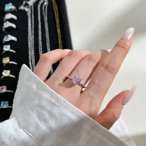 Macro view of heart-shaped pink zircon ring with silver band on a finger