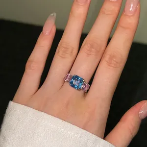 Primer plano de anillo de plata S925 con circonitas cuadradas azul y rosa en el dedo