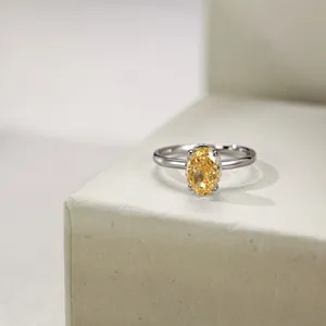Macro shot of oval cut yellow gemstone with four-prong setting on silver ring band