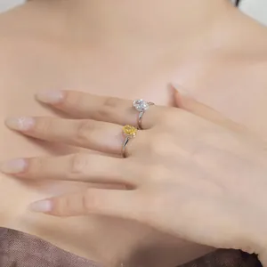 Close-up of hand wearing two oval-cut zircon rings with silver bands and yellow gems