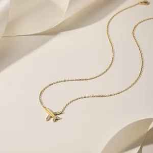 Close-up of golden airplane pendant necklace with sparkling cubic zirconia on white silk