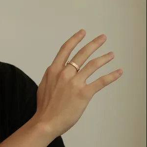 Close-up of a rose gold matte ring with pavé zircons worn on a finger