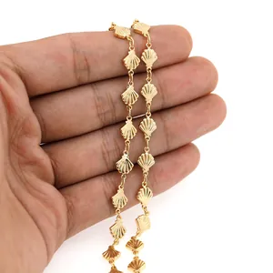Detailed view of 18K gold-plated scallop chain on palm showing textured metallic luster