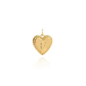 Macro detail of 18K gold plated heart pendant with letter F and sunburst texture