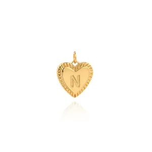 Macro shot of 18K gold plated heart pendant with embossed letter N and radial texture