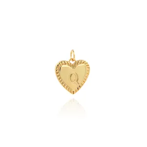 Close-up of 18K gold heart pendant with letter Q engraving and vintage textured edges