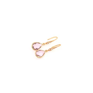 Dettaglio di orecchini a goccia dorati con pietre rosa e delicate perle bianche