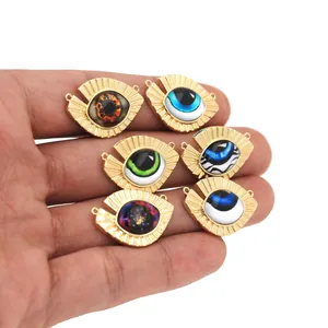 Macro shot of 18K gold-plated Evil Eye charms with colorful enamel eyes in hand