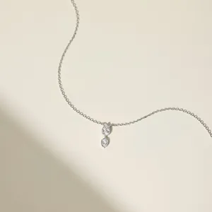 Detail van zilveren ketting met dubbele verticale druppelhangers ingelegd met zirkoon