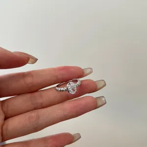 Detailed view of an oval-cut zircon ring with beaded band design on a female hand