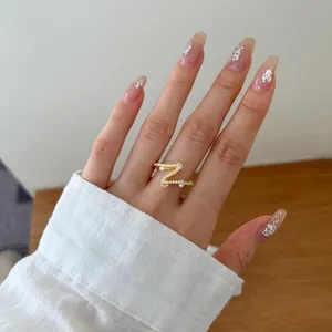 Close-up of gold-plated Z-shaped ring with pavé zircons worn on hand for daily style