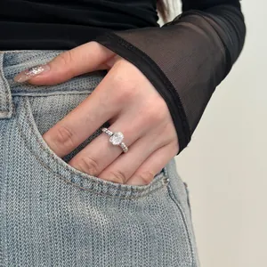 Close-up of S925 silver ring with oval cubic zirconia on hand with denim background