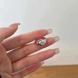 Macro detail of S925 sterling silver ring with bezel-set heart zircon on finger