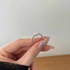Close-up of a 925 silver ring featuring a pink oval zircon and beaded band on a finger