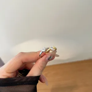 Close-up of silver and gold heart zircon rings held by hand to show fine metallic luster