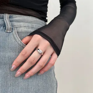 Close-up of a silver heart-shaped zircon ring worn by a model in casual black outfit