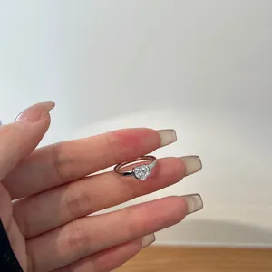 Macro detail of a heart-shaped zircon inlay on a minimalist S925 sterling silver ring