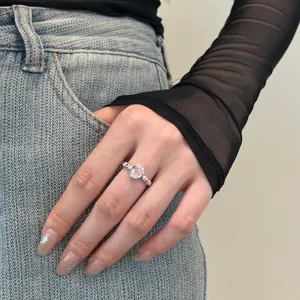 Close-up of a s925 silver ring with a pink oval zircon on a model's hand with fashion outfit