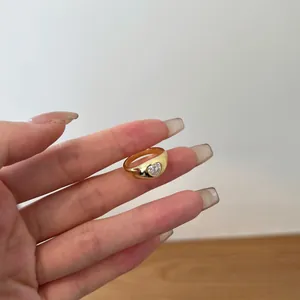 Close-up of golden heart-shaped zircon ring with wide band on a female model