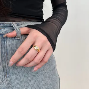 Close-up of a wide gold band ring featuring a heart-shaped zircon on a model's hand