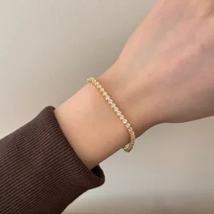 Close-up of a delicate gold tennis bracelet with single row cubic zirconia on a wrist