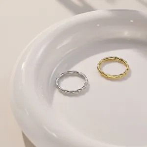 Close-up of twisted s925 silver and gold rings on a white minimalist ceramic tray