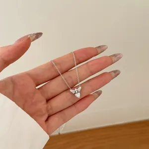 Makroaufnahme einer silbernen Bienenhalskette mit Herz-Zirkonia auf einer Hand