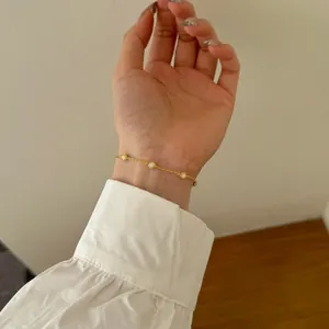 Detalle de la pulsera dorada con perlas de nácar en la muñeca para un estilo minimalista chic