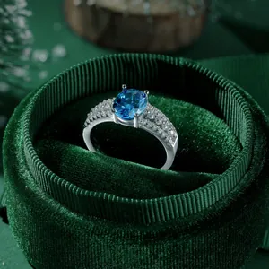 Macro shot of an oval blue gemstone ring with micro-pave zircons in a green velvet box