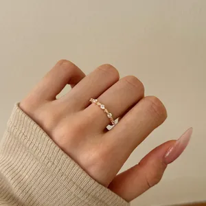 Detailed view of rose gold S925 silver ring with zircons on a hand with nude nails