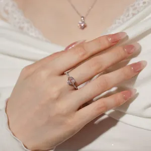 Close-up of heart-shaped zircon ring with rose gold bow detail on a hand
