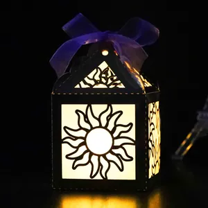 Macro shot of black paper house lantern with sunburst laser cutouts and purple ribbon