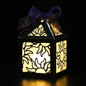 Close-up of golden paper lantern with hollow sun pattern and purple ribbon bow