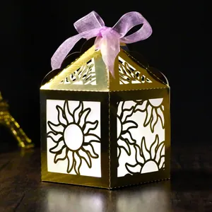Detail of golden laser-cut solar gift box with purple organza bow and glowing light